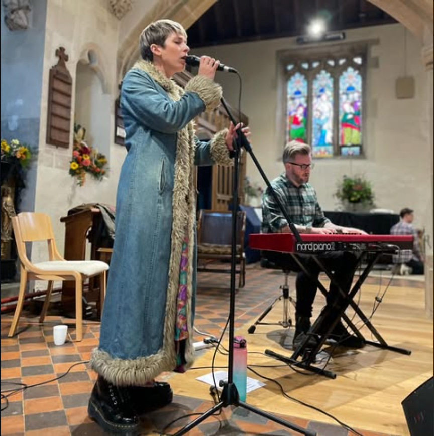 A singer and keyboard player performing inside a church